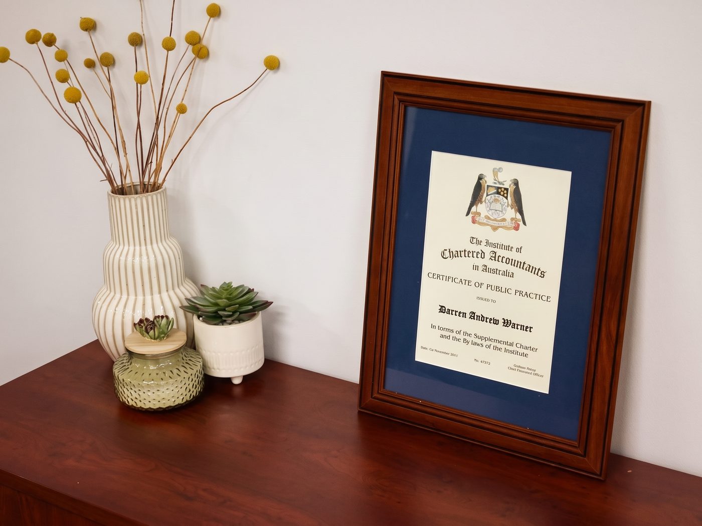 Darren Warner's Certificate of Public Practice from the Institute of Chartered Accountants in Australia, framed on a sideboard in the DWA office